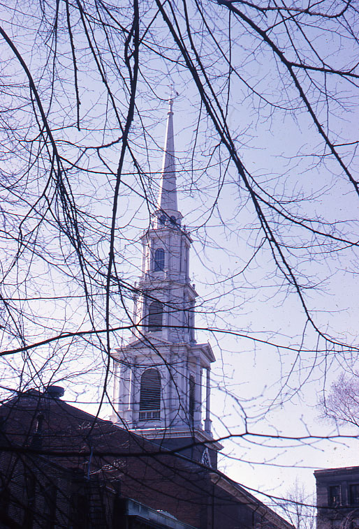 the large steeple of a building rises above the surrounding buildings