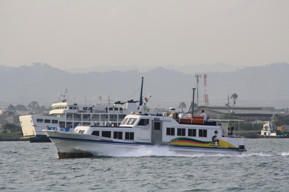 a large ferry is cruising on the ocean with two smaller boats next to it