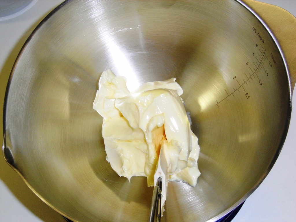 a large metal bowl containing a batter and cream