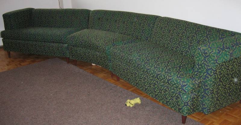 an odd couch sitting in a corner between a rug and a wall