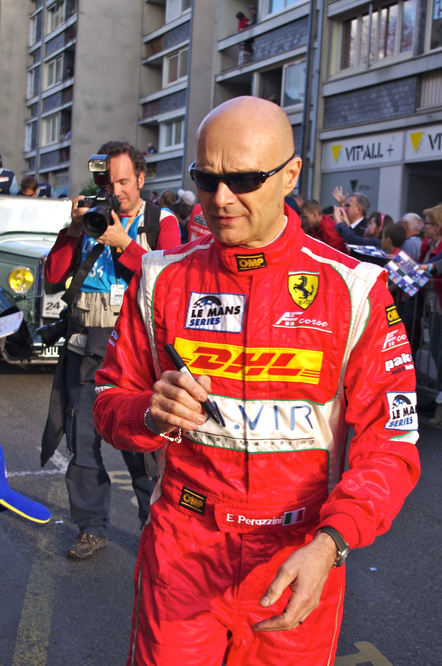 a man in red racing suit standing on street next to building