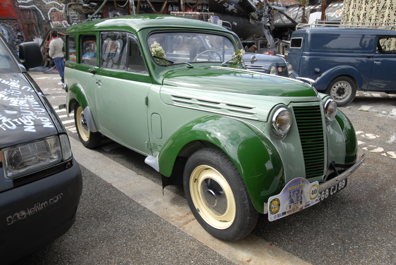 a green and white old car is on a city street