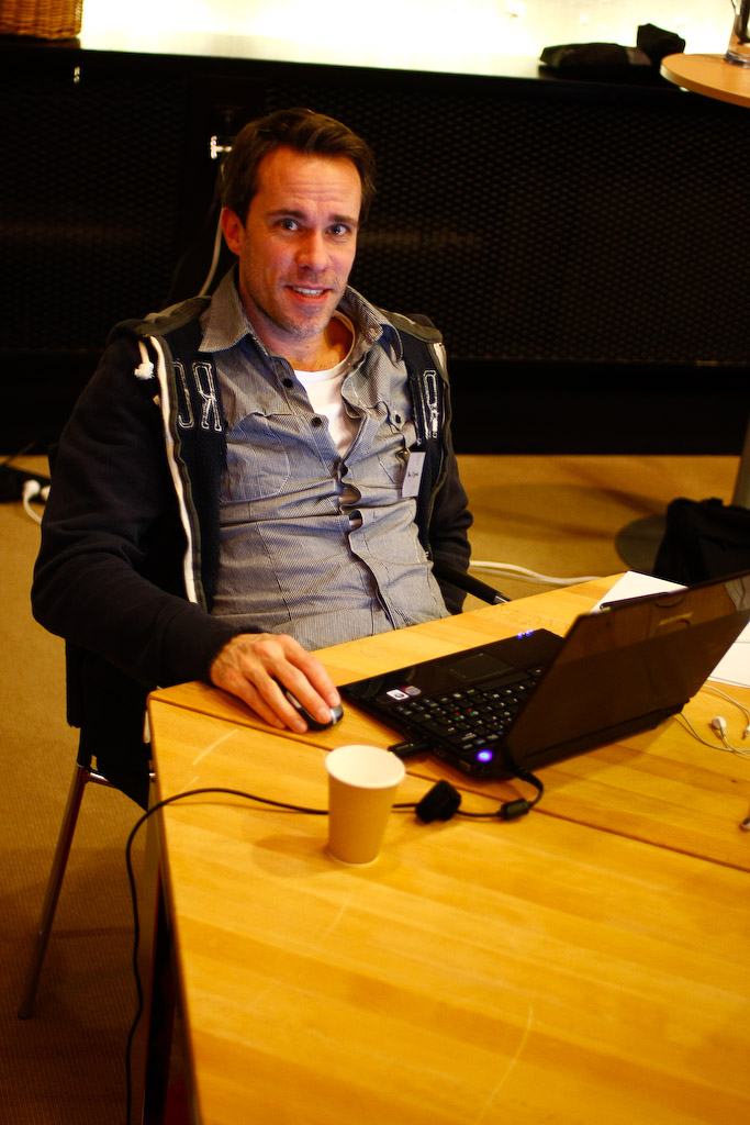 man sitting at a wooden desk with headphones on