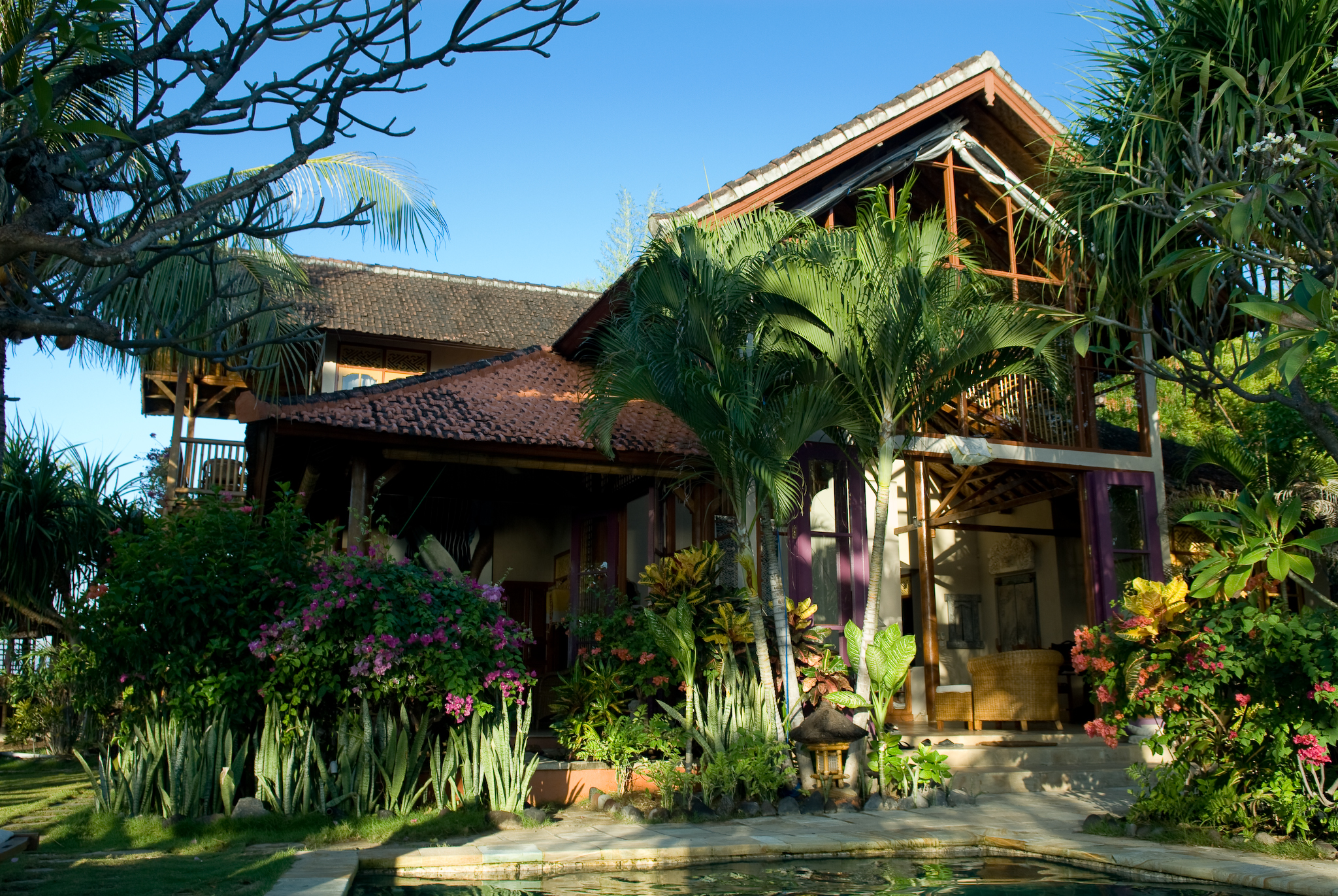 an older house with lots of trees and flowers