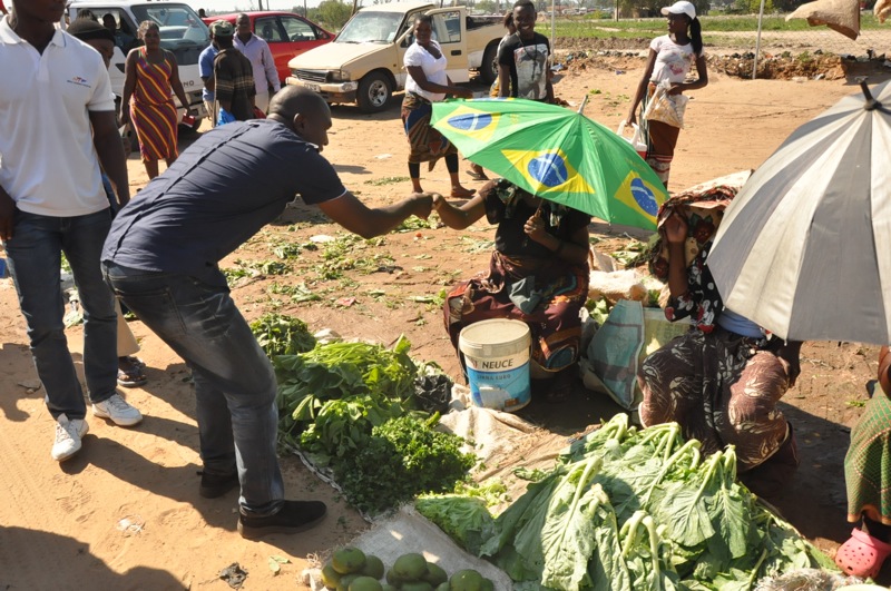 people shopping and selling fruits and vegetables on a dirt road