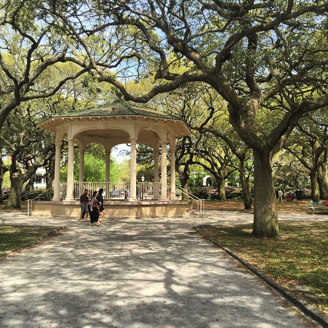 two people stand near each other in front of a pavilion and trees