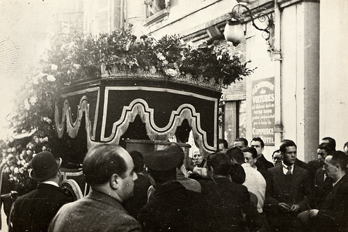 black and white po of a man standing next to an ornate casket