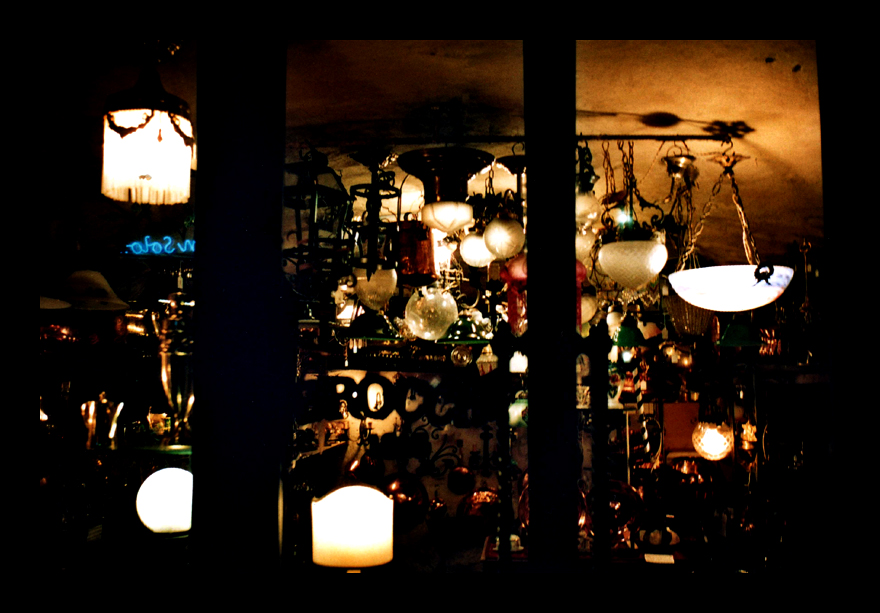 a dark room with several hanging lights, a mirror and a clock