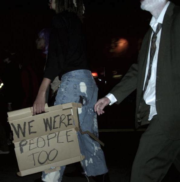 a man holding a sign while walking past another man in the street
