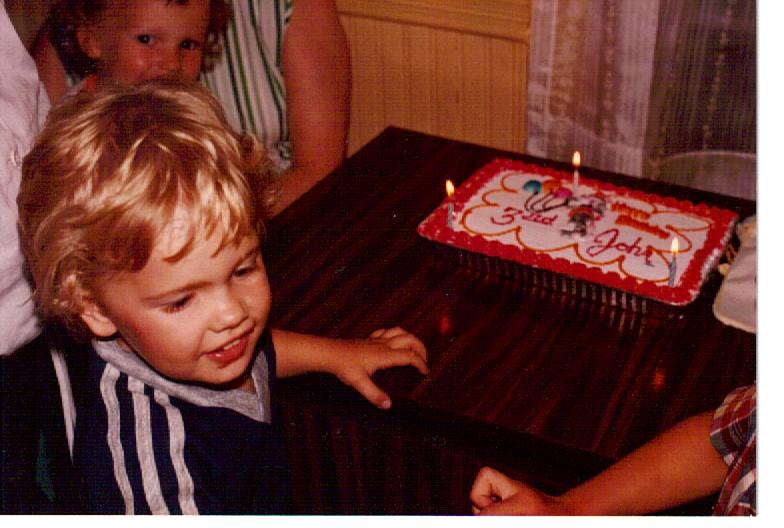 a  standing next to a birthday cake with candles