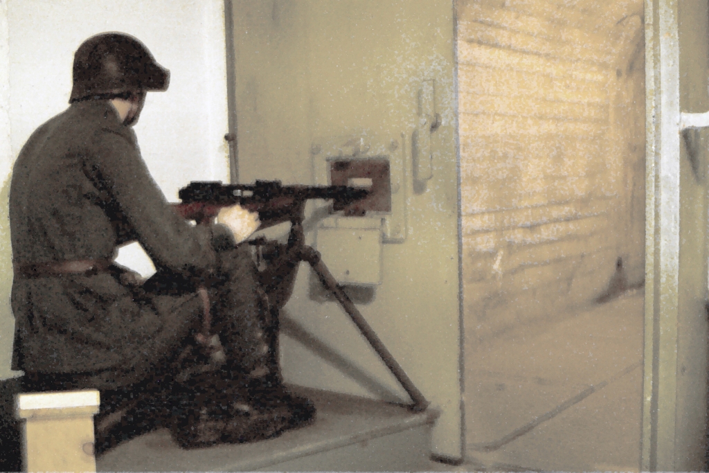 a soldier in uniform and with a gun sitting on the floor