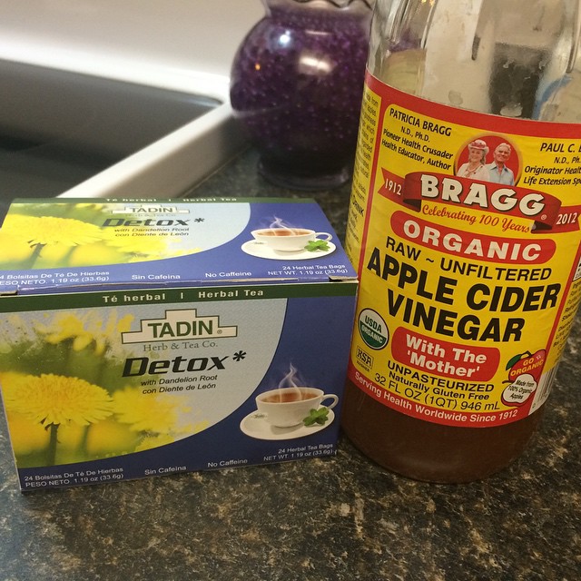 a bottle of apple cider vinegar sitting next to a box of fruit