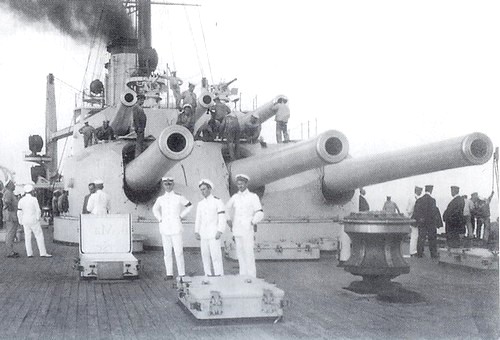 a group of sailors standing next to a large gun