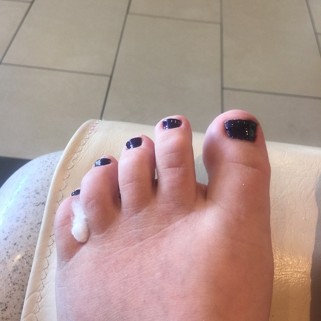 the female feet are adorned with black manicures