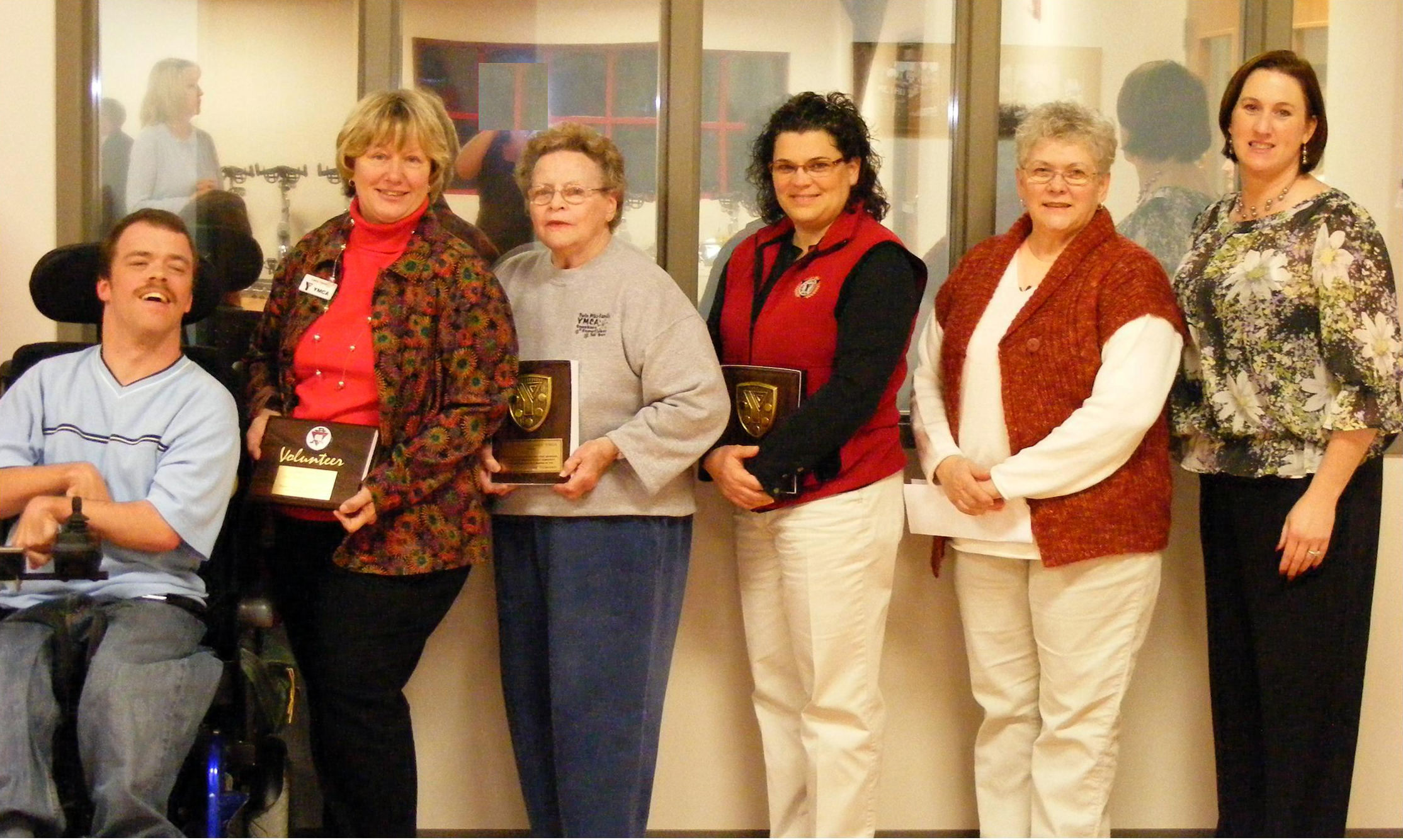 group of women holding award items for people with a paramed wheelchair