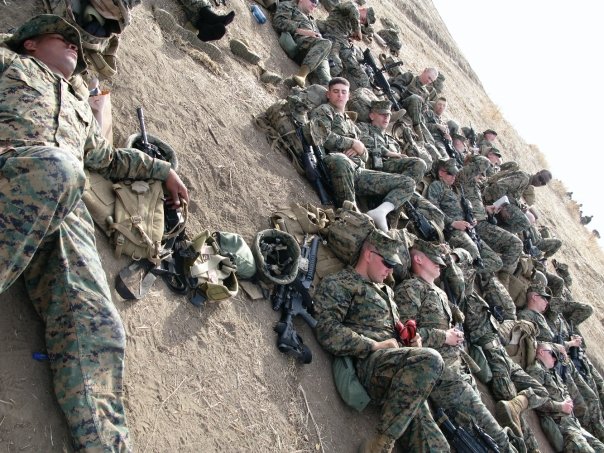 several men in camouflage uniforms and helmets laying on ground next to wall