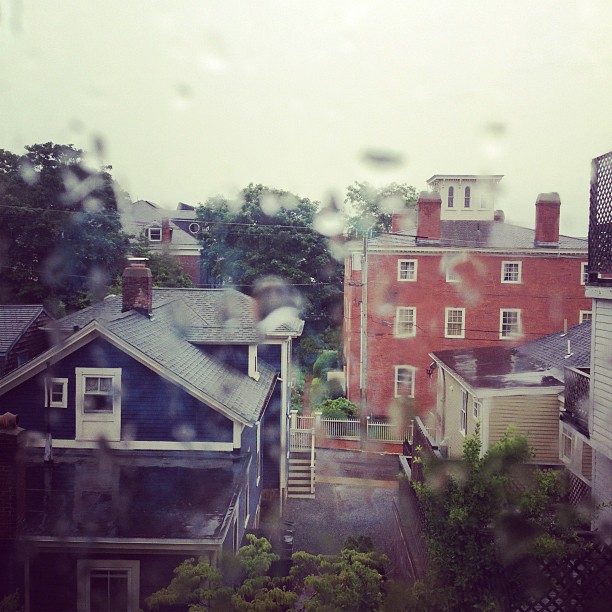 an overcast sky shows rain coming down on houses