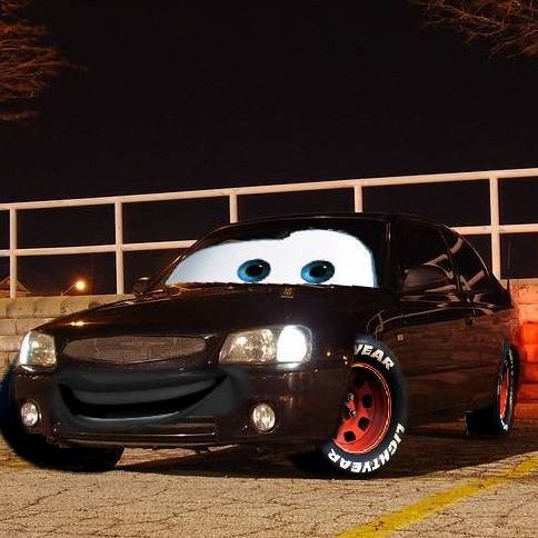 a black car with eyes on the front sitting in parking lot