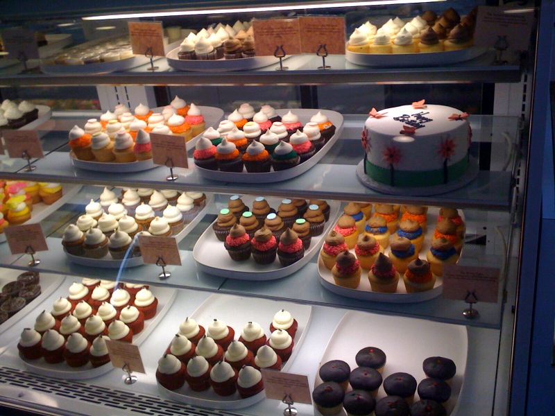 an assortment of different colored cupcakes on display