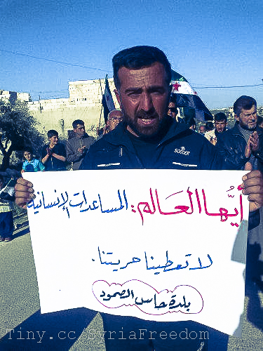 a man holding a protest sign, holding up a banner and looking directly ahead