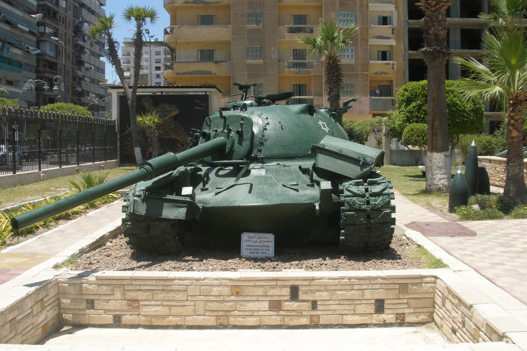 the large green tank is parked in a garden