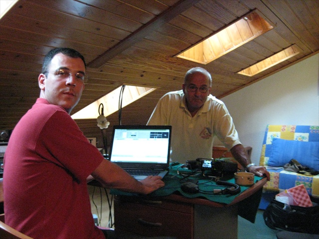 two men work on a laptop inside of an old school house