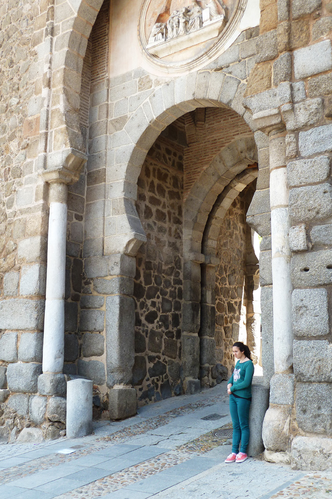 a woman standing next to an old stone wall