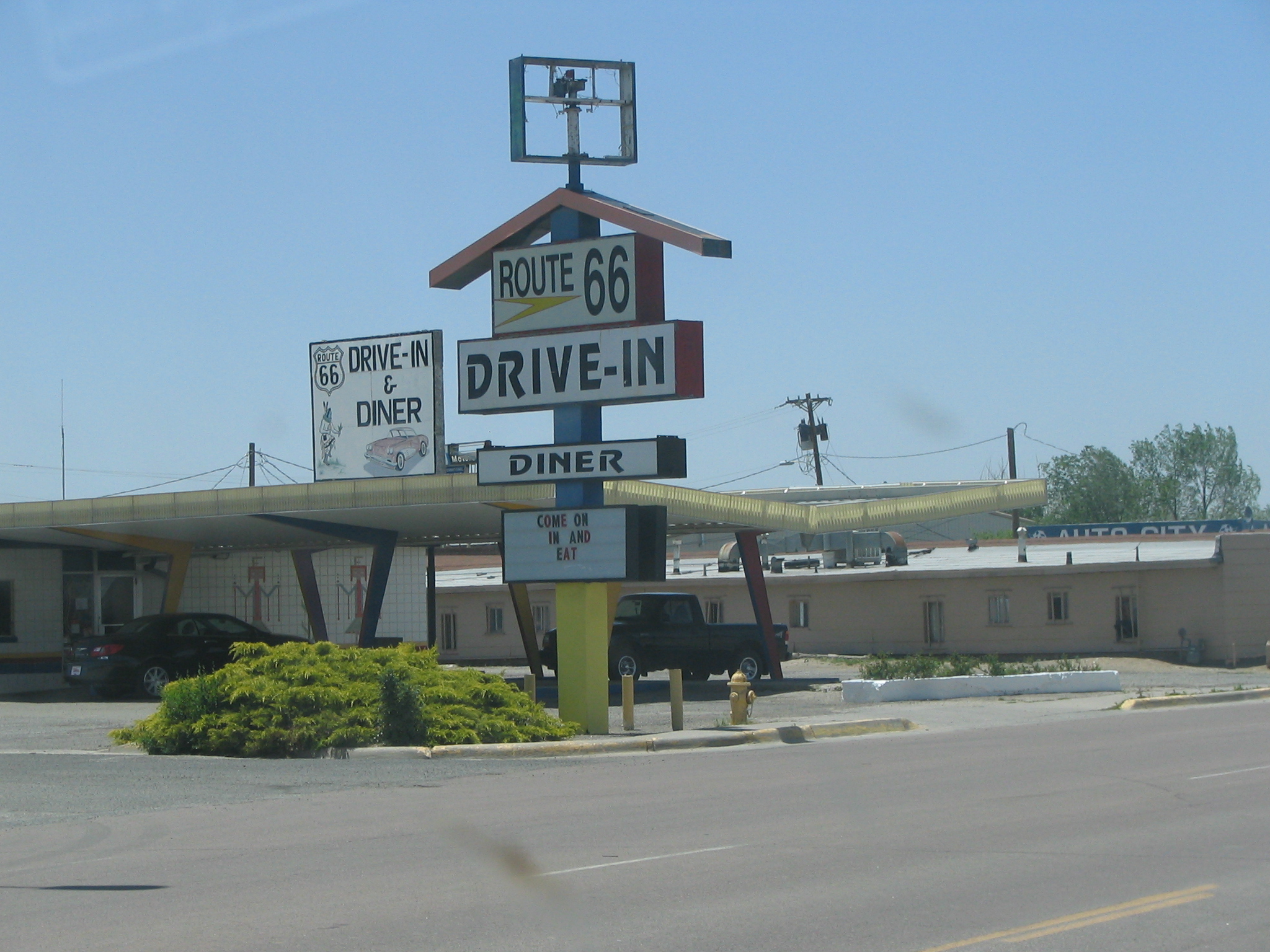 a sign advertising route 66 drive in near an empty intersection