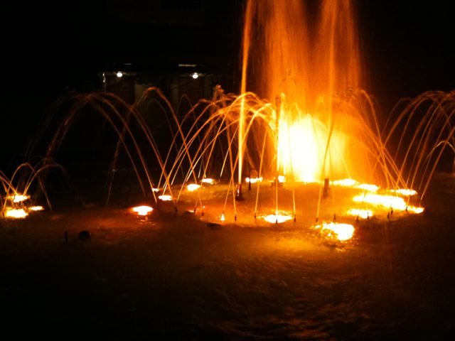a lit display of fountains is pictured in the dark