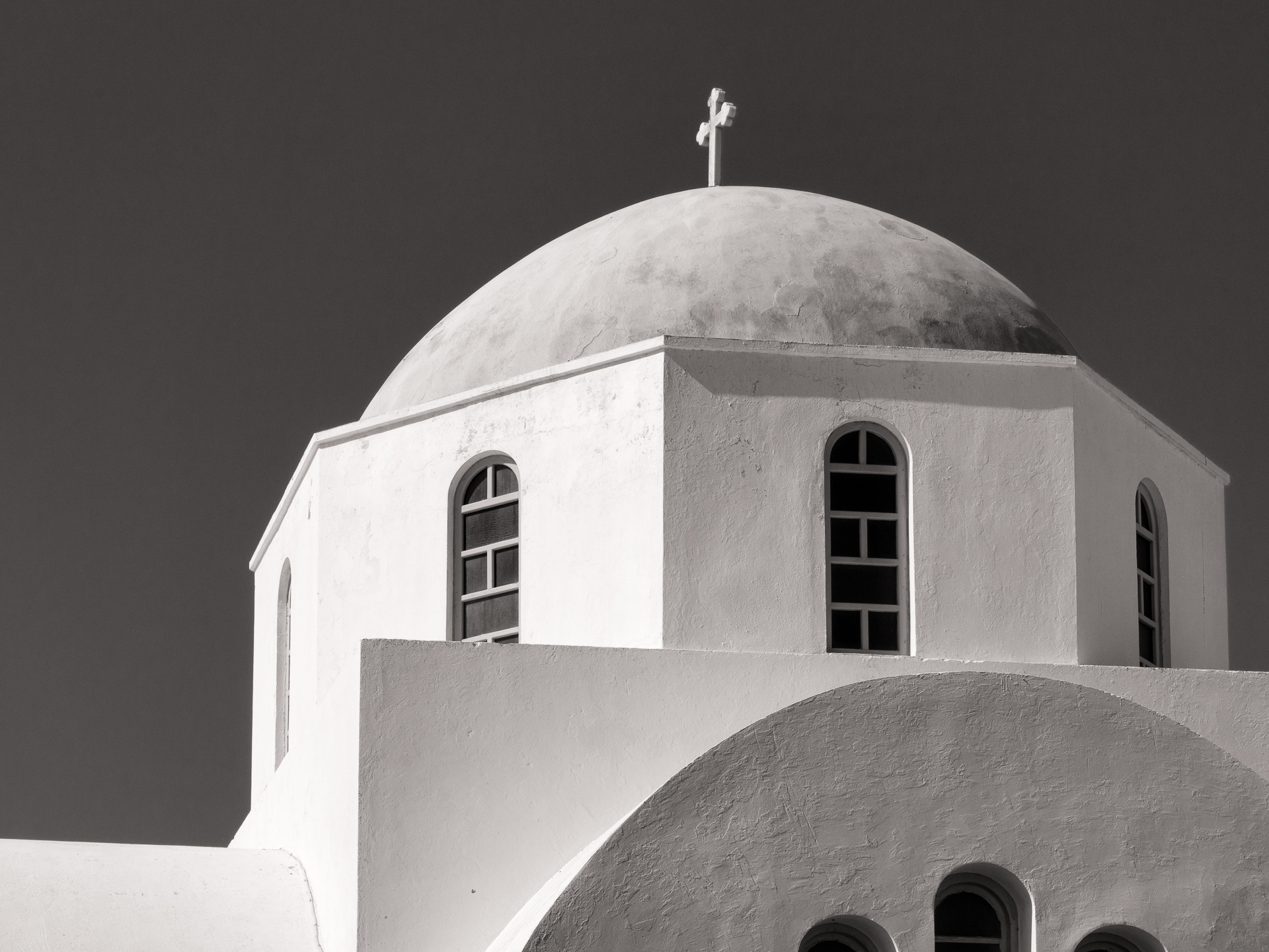 the roof of a white building has two arched windows