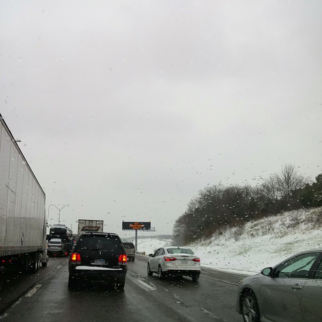 three vehicles are on the freeway in the snow