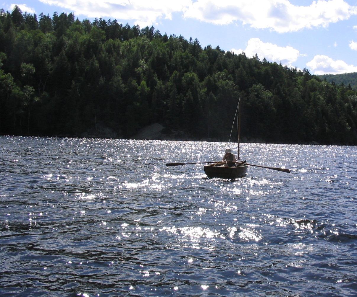 a person on a small boat in the water with trees in the background