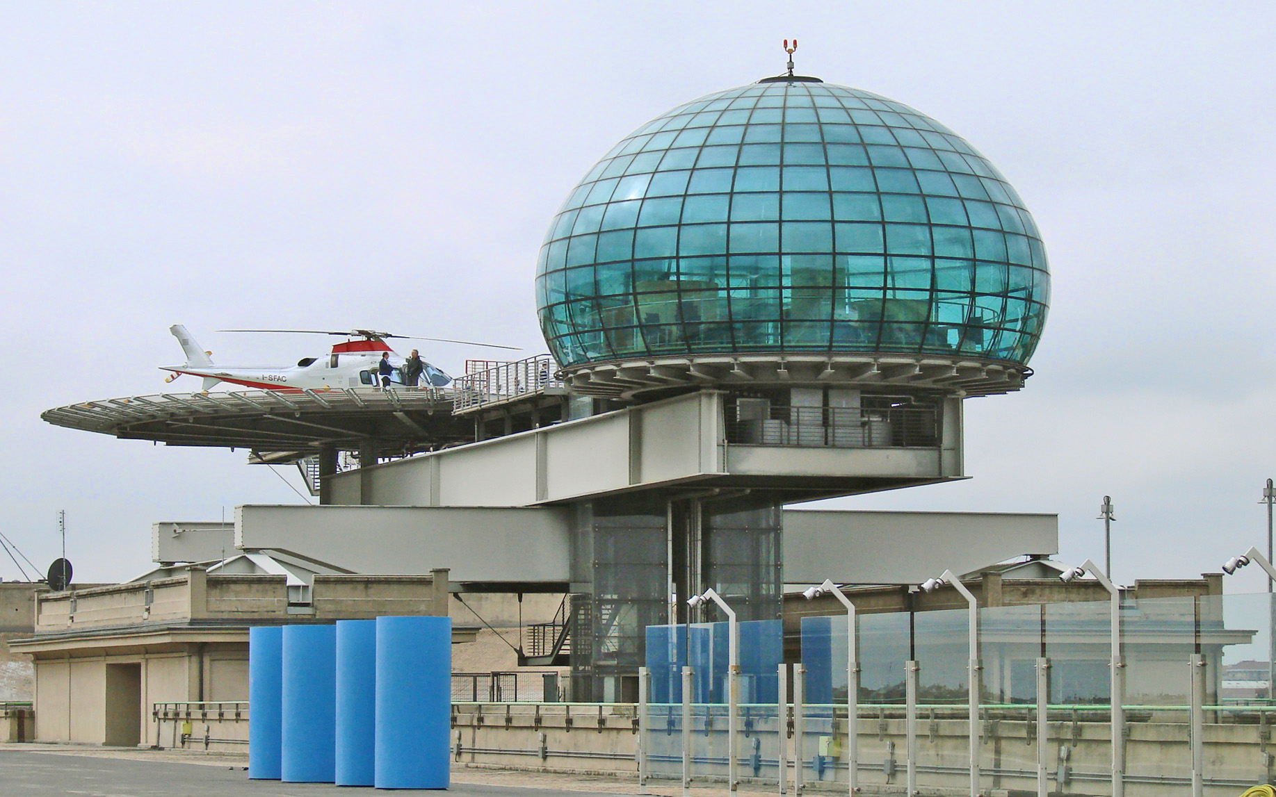 a couple of men are standing in a helicopter hangar