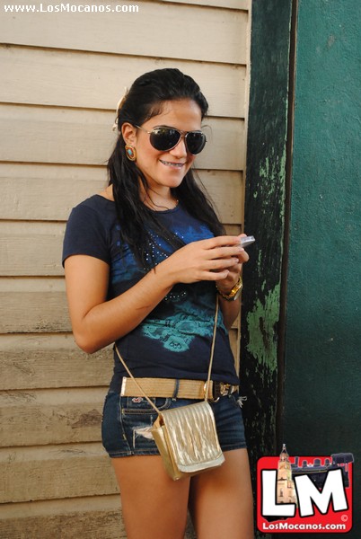 girl wearing dark sunglasses leaning on the door of a small building
