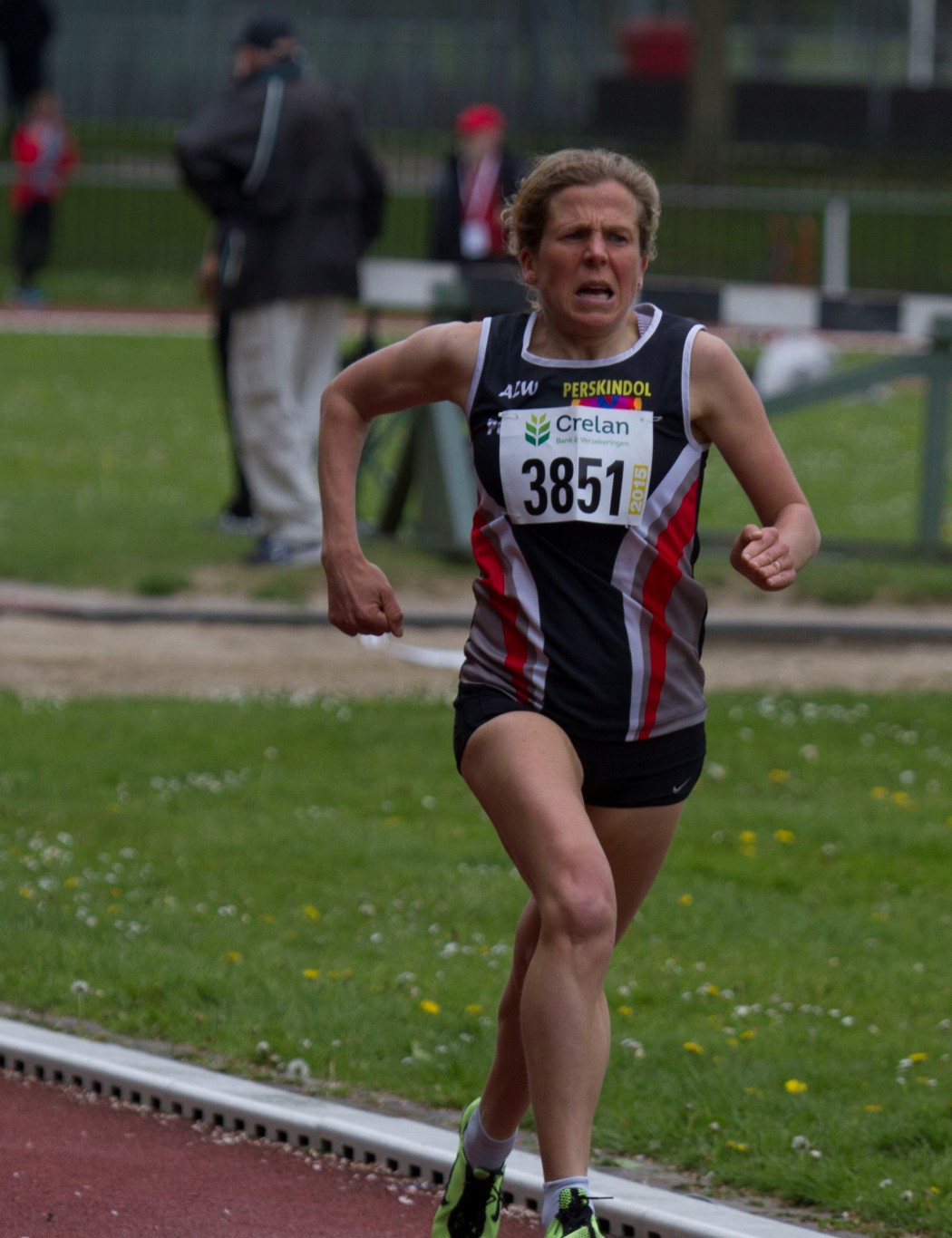 a woman running down a street with green grass