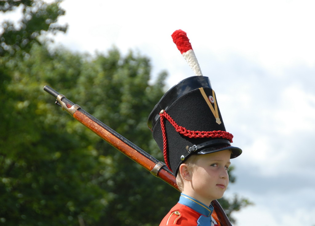 a boy in a marching uniform with a rifle