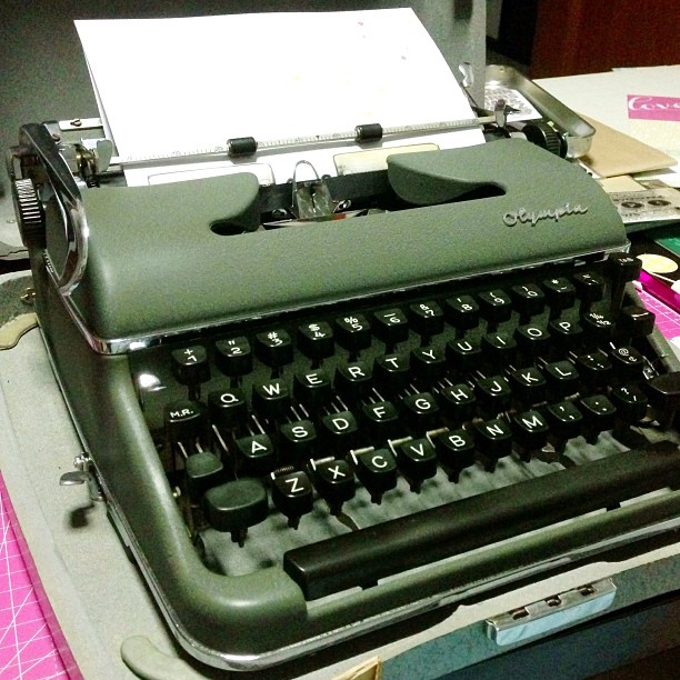 an old fashioned typewriter sits on top of a cluttered desk