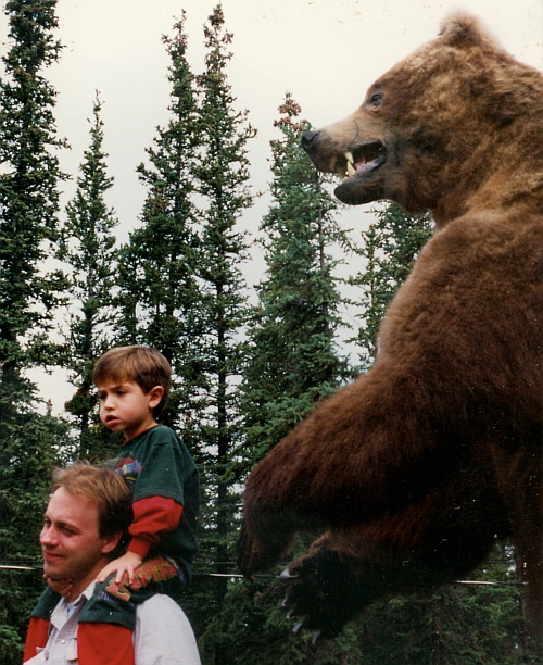 a boy sitting on the back of a stuffed bear