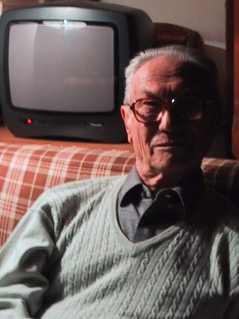 an old man with glasses sitting on the couch