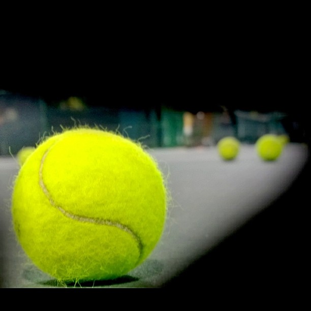the tennis ball is in motion with many other balls nearby