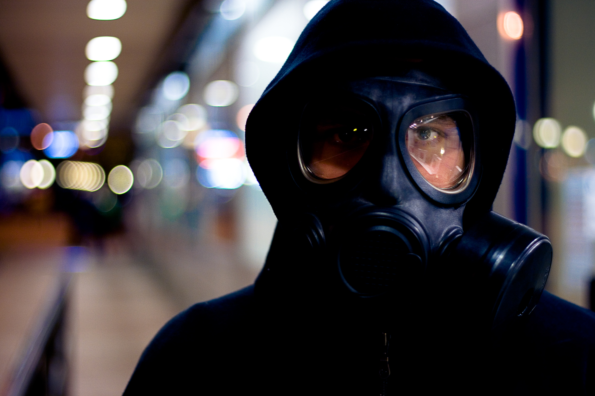 man in gas mask walking on city street at night