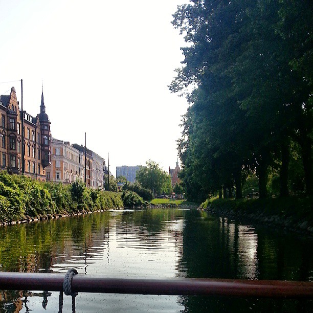a view of a river on a sunny day with old buildings and trees