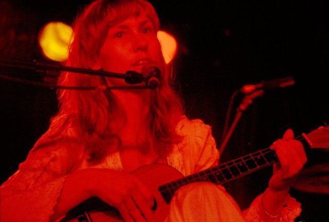 a young woman playing an instrument while sitting in front of a microphone