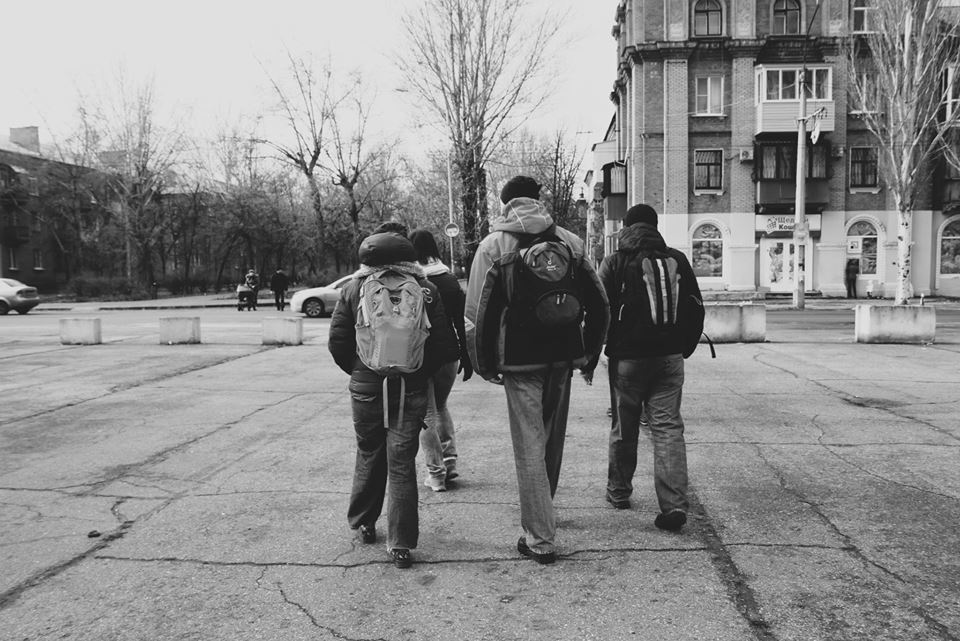 three boys with backpacks walking down the street