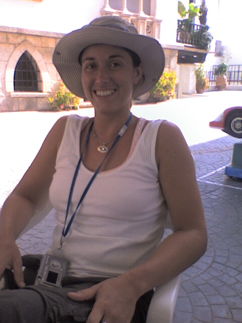 a smiling woman wearing a hat holding a camera