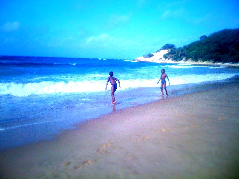 two people are walking on a beach near the ocean