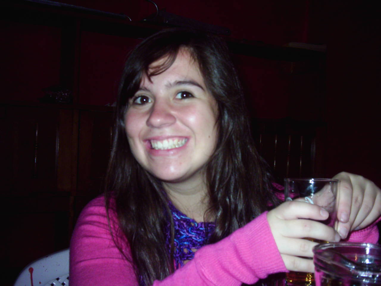 a smiling woman in pink is holding up a glass