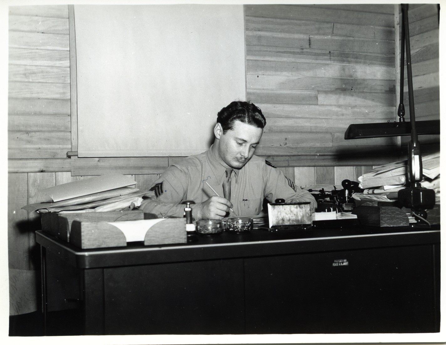 black and white po of a man sitting at a desk working on some paperwork