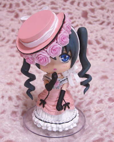a small, cute doll in a hat on a pink table