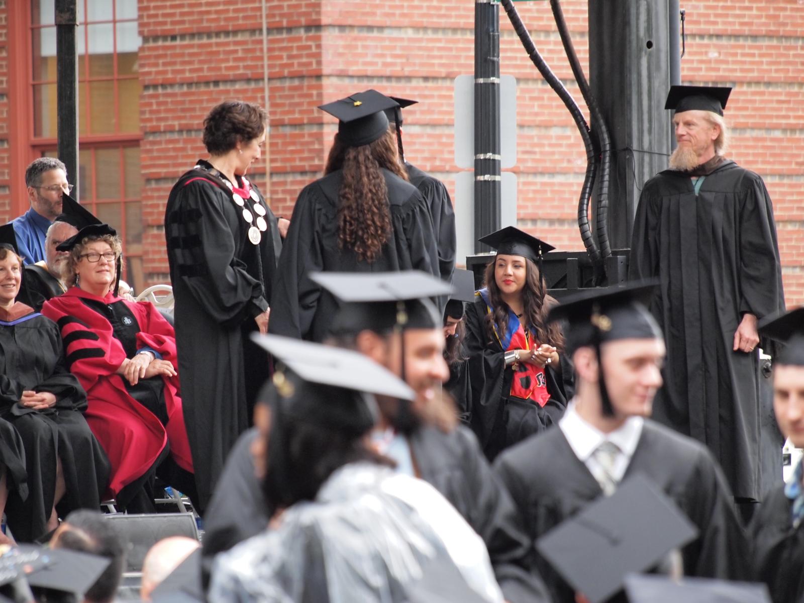 graduates in graduation robes stand together at a graduation ceremony